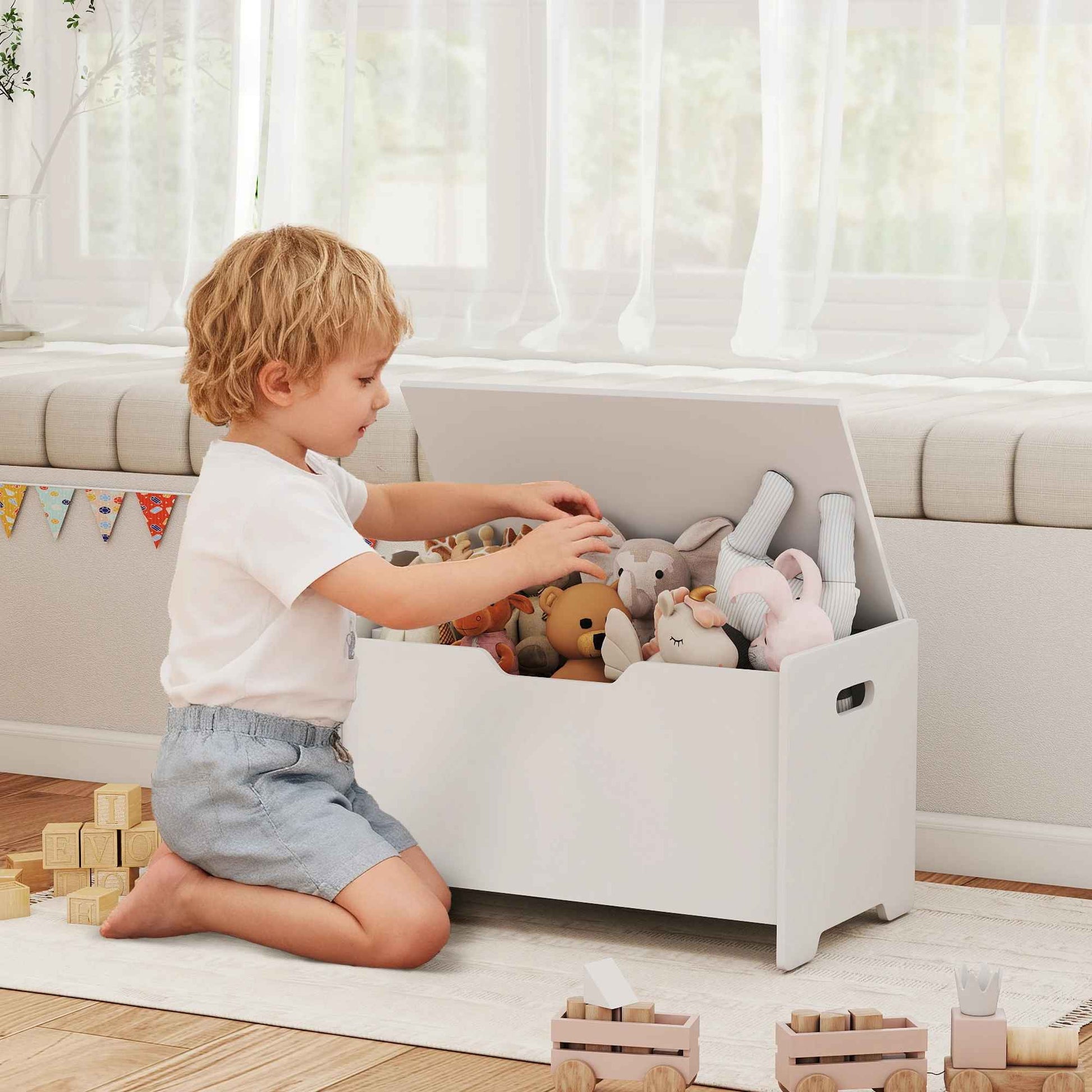 Enfant qui range ses peluches dans le coffre de rangement